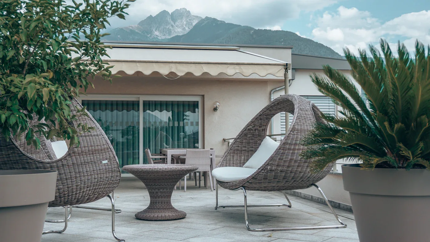Woven outdoor chairs and a small round table on a terrace