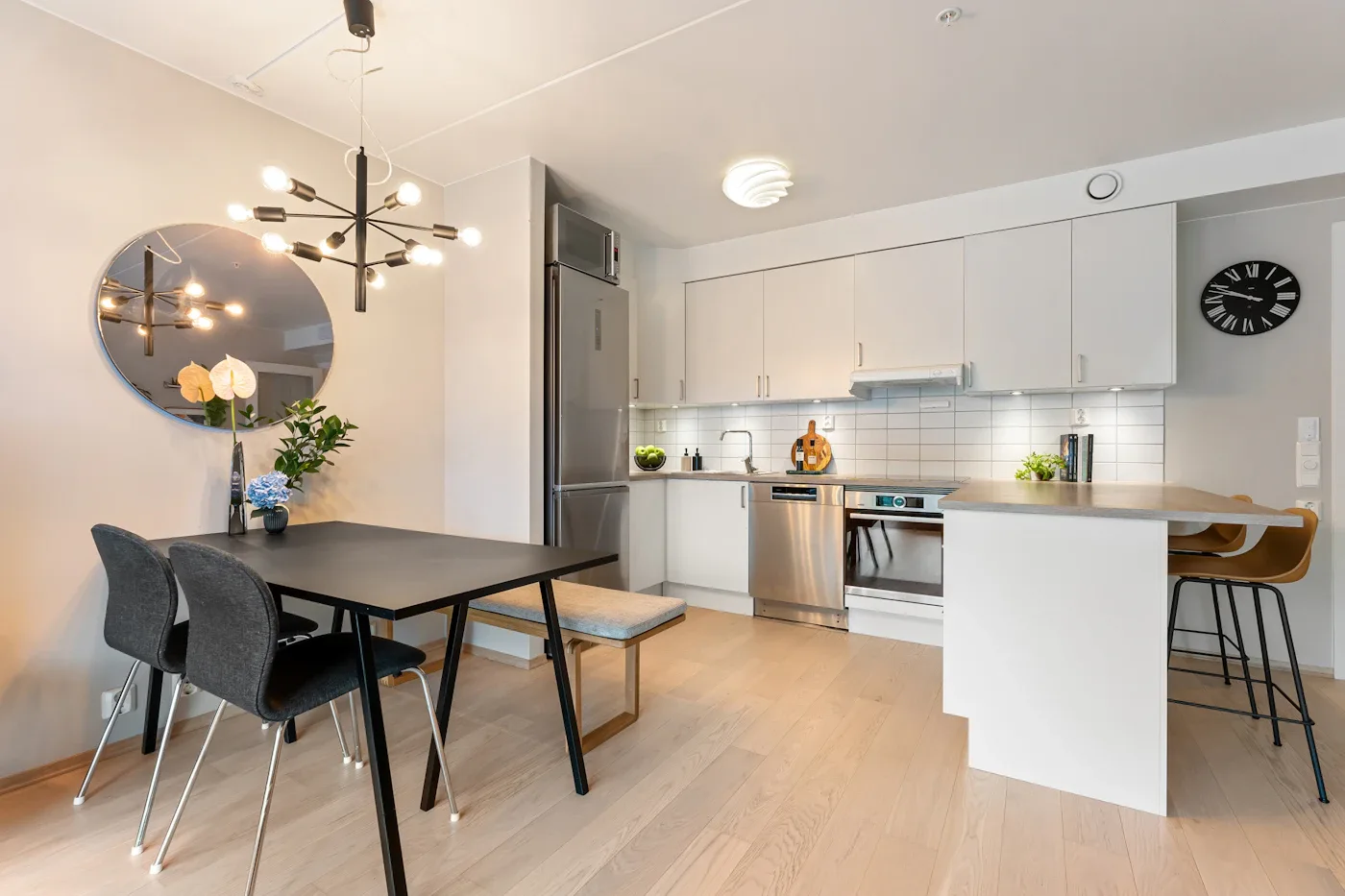 Dark dining table and chairs beside a white kitchen