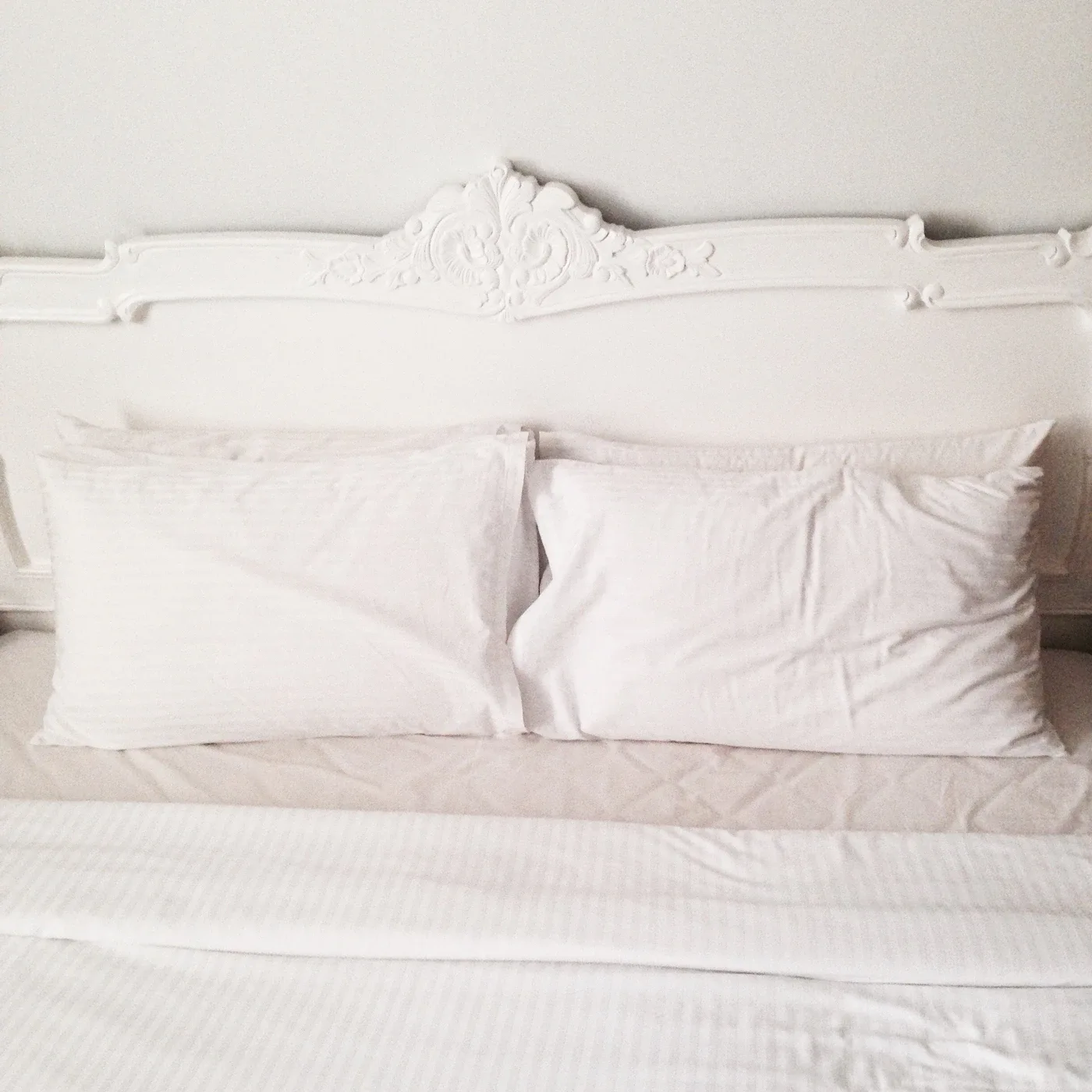 White pillows resting on neatly made pale bedding
