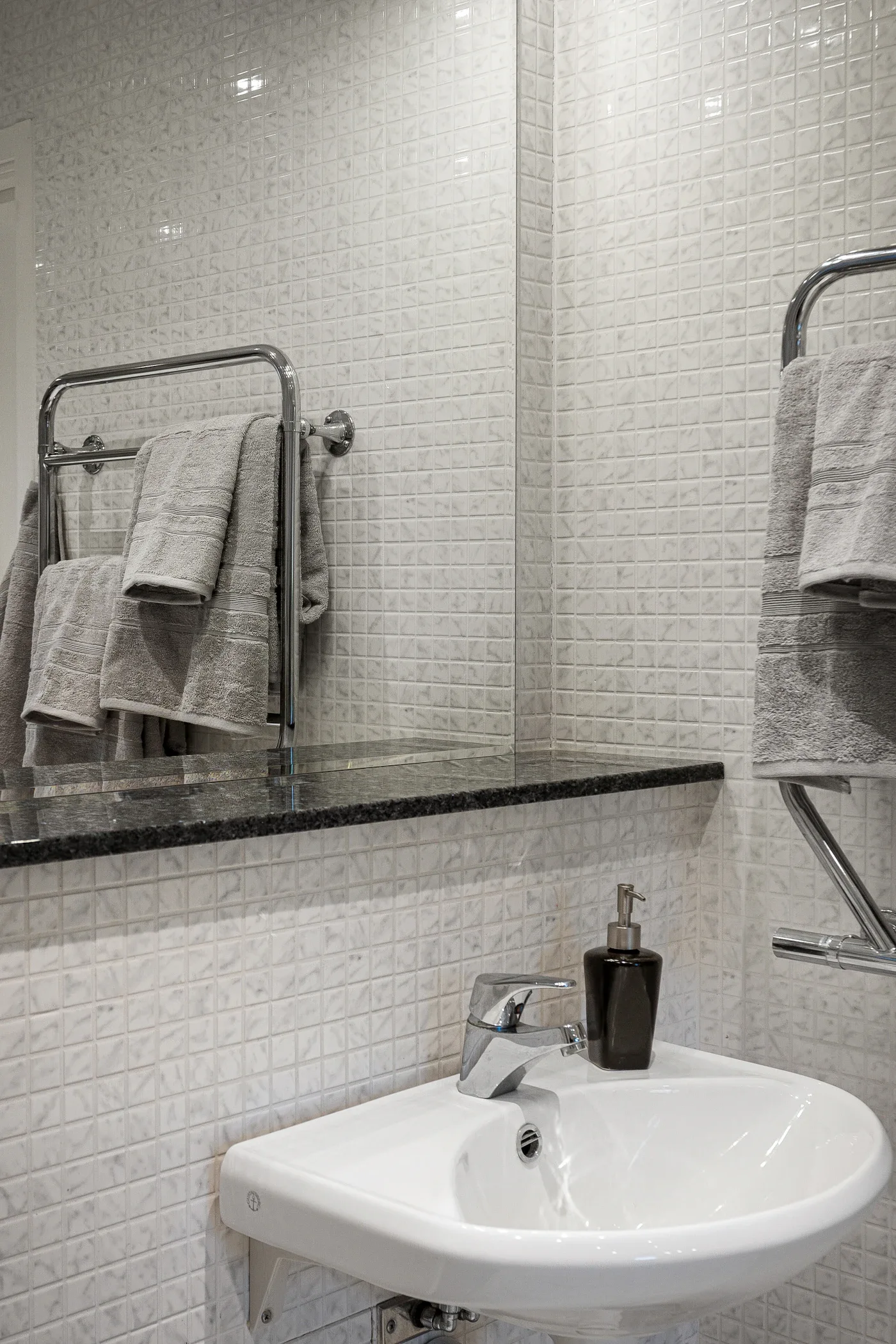 Gray towels on a wall-mounted rack in a tiled bathroom